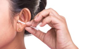Close up woman cleaning her ear by using cotton bud stick isolated on white background
